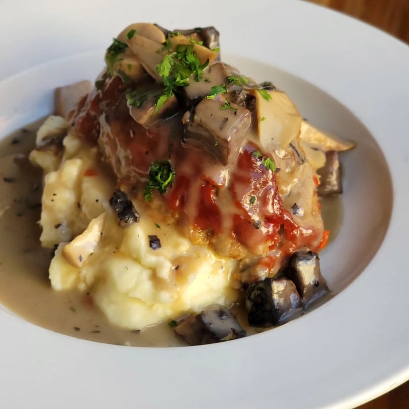 Butcher Bar's mashed potatoes topped with meat, gravy, mushrooms, and fresh parsley.
