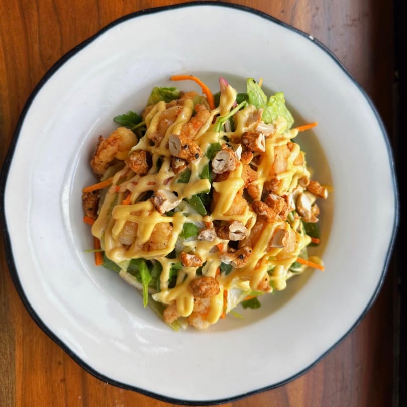 Butcher Bar's fried shrimp and greens salad, drizzled with creamy dressing and topped with nuts.