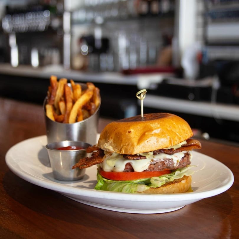Butcher Bar's bacon cheeseburger with lettuce, tomato, and a side of fries and ketchup.